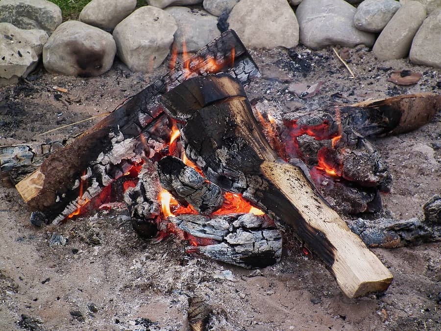 Un feu de bois et ses braises rouges au milieu de pierres : le feu dont parle la phrase.