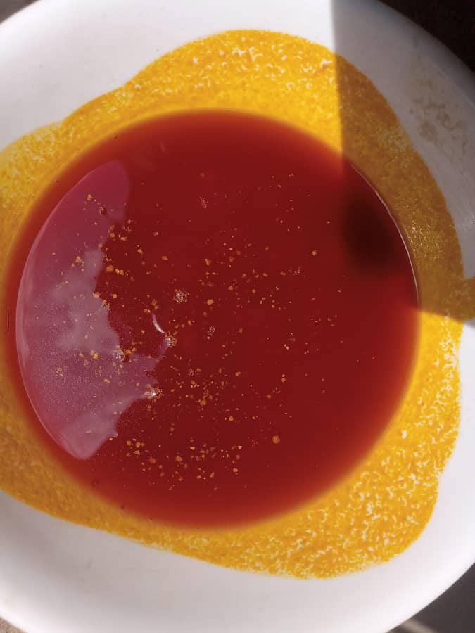De l'huile de palme rouge dans un bol blanc : l'huile dont parle le proverbe.