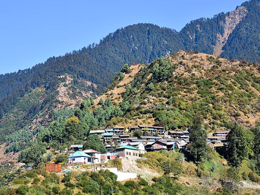 Un village de montagne serré sur son versant boisé : le village dont parle la phrase.
