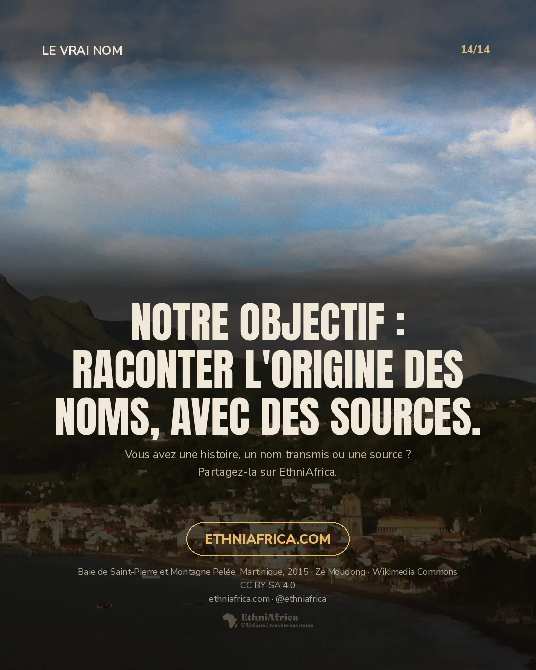 La Montagne Pelée en lumière de fin de journée au-dessus de la ville de Saint-Pierre, aux toits blancs et rouges et au clocher, au bord d'une baie sombre où mouillent quelques voiliers.
