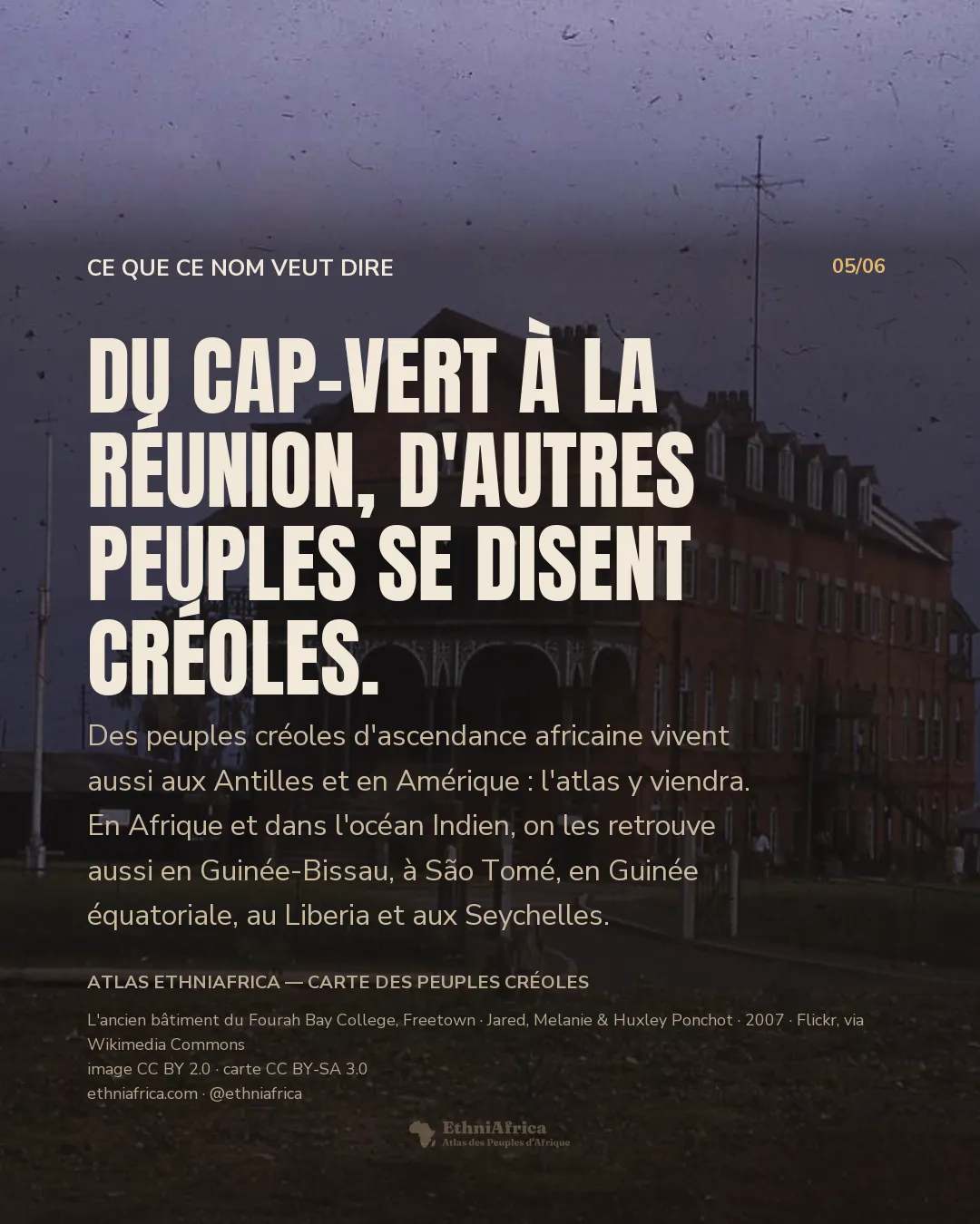 un grand bâtiment victorien en brique rouge à véranda et lucarnes, photographié au crépuscule sous un ciel orageux, un palmier isolé à droite et une silhouette lointaine sur le chemin