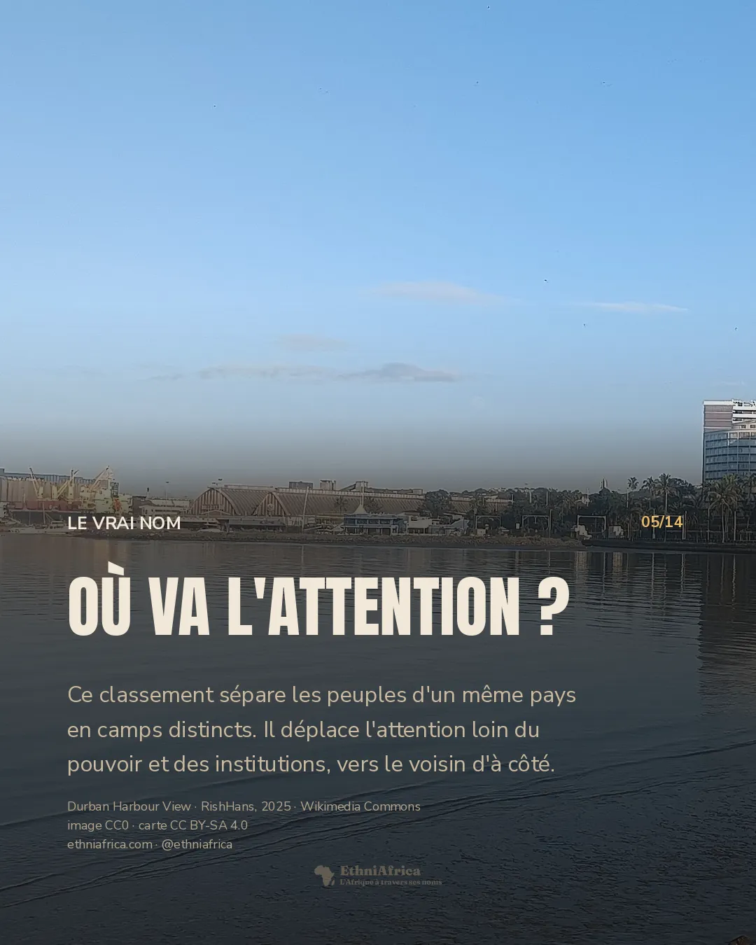 vue d'un port au bord de l'eau, avec des immeubles clairs sous un ciel bleu et des rochers au premier plan